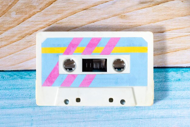 Vue supérieure d'une cassette de musique avec des étiquettes rétro colorées sur un fond de bois colorés