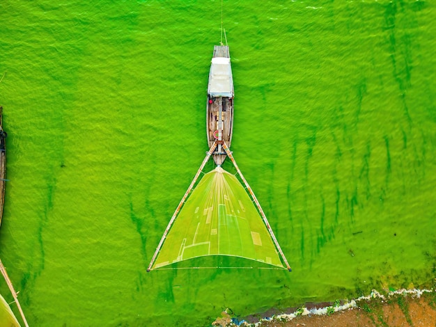 Vue supérieure du village de pêcheurs de Ben Nom image verte fraîche de la saison des algues vertes sur le lac Tri An avec de nombreux bateaux de pêche traditionnels ancrés à Dong Nai au Vietnam