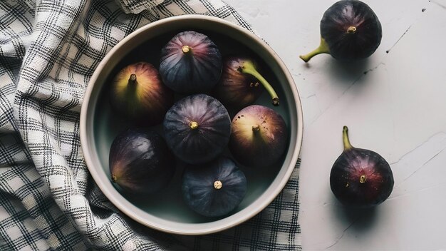 Vue supérieure de figues de mission noires douces sur un bol sur un tissu à carreaux sur une surface blanche