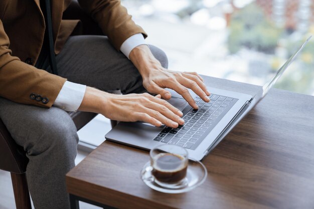 Vue supérieure d'un homme d'affaires intelligent travaillant à la main en tapant à l'aide d'un ordinateur portable Ornamenté