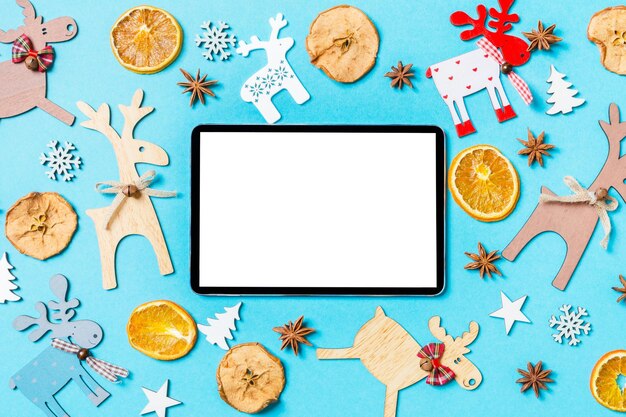 Vue supérieure d'une tablette numérique sur fond bleu faite de décorations de vacances et de jouets Concept d'ornement de Noël
