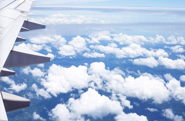 Vue sur terre, nuage et aile d'avion depuis la fenêtre