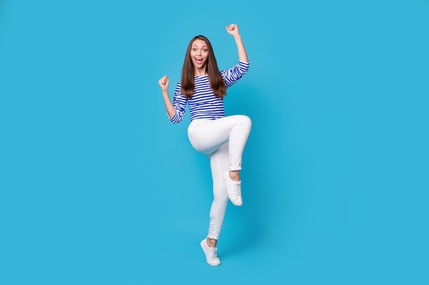 Vue sur toute la longueur du corps d'elle, elle belle jolie fille gaie et gaie portant un saut occasionnel se réjouissant de s'amuser danser isolé sur fond de couleur bleu vif brillant éclatant