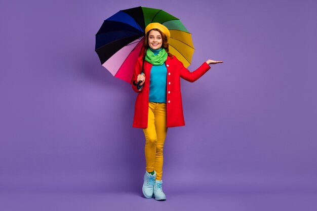 Vue sur toute la longueur du corps d'une jolie jolie fille aux cheveux ondulés assez gaie tenant un espace de copie de parapluie sur la paume vérifiant la goutte de pluie isolée sur fond de couleur pastel violet lilas violet