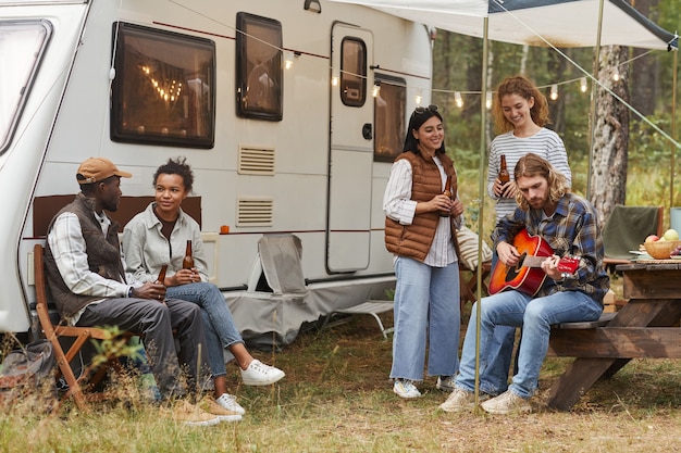 Vue sur toute la longueur d'un groupe de jeunes se relaxant à l'extérieur en camping-car dans l'espace de copie d'automne