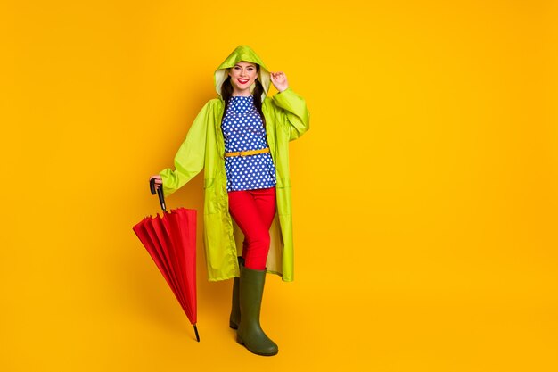 Vue sur toute la longueur de la taille du corps d'elle, elle est jolie, jolie, jolie, glamour, à la mode, gaie, gaie, fille, portant une cape de capuche, posant isolée, brillante, éclatante, fond de couleur jaune vif