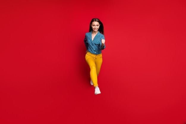 Vue Sur Toute La Longueur De La Taille Du Corps D'une Jolie Fille Mince Et Joyeuse Sautant En Mouvement Isolé Sur Fond De Couleur Rouge Vif