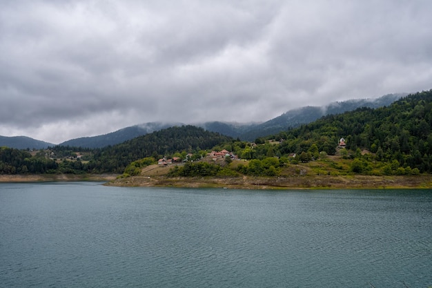 Vue tranquille du village de montagne éloigné avec lac dans un matin d'été brumeux nature plein air voyage de