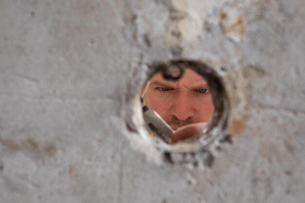 Vue sur le trou dans le mur où le bricoleur répare les fils en les coupant