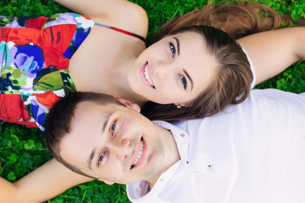 Vue vers le haut heureux jeune couple allongé sur l'herbe dans le parc à l'extérieur Ils profitent du beau temps