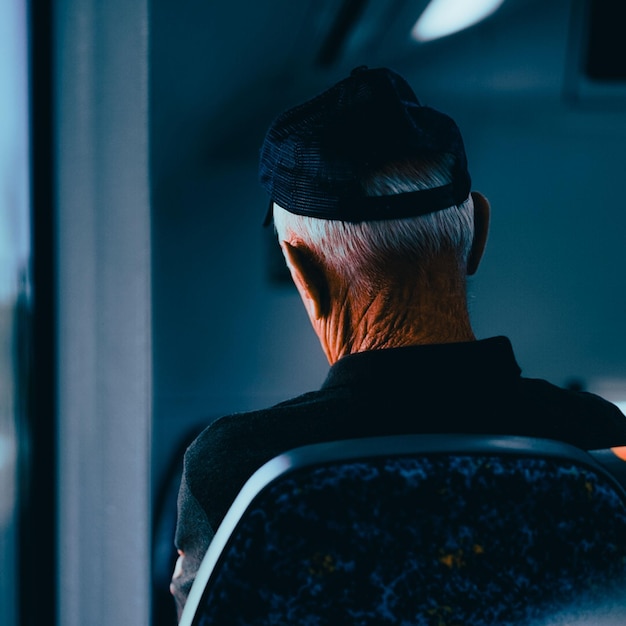 Vue verticale arrière d'un vieil homme assis avec un cou ridé et un chapeau