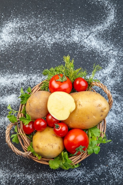 Photo vue verticale des crudités et du vert dans un panier en bois sur un fond blanc noir