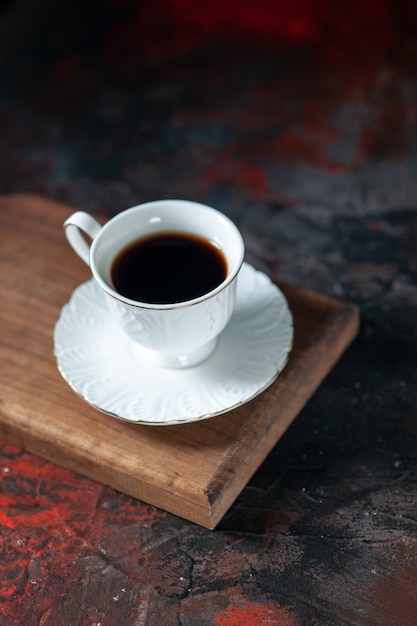 Vue verticale d'un délicieux café dans une tasse blanche sur une planche de bois marron sur fond de couleurs sombres mélangées avec espace libre