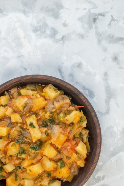 Vue verticale d'un délicieux dîner avec pommes de terre légumes verts dans un bol marron sur fond de glace avec espace libre