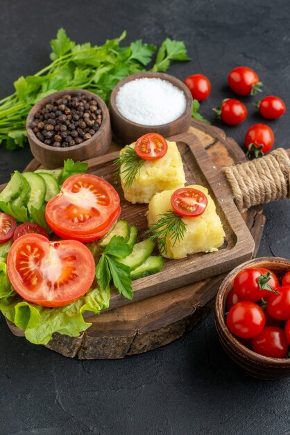 Vue verticale du fromage de légumes frais hachés sur planche à découper et épices vert bundle sur surface noire