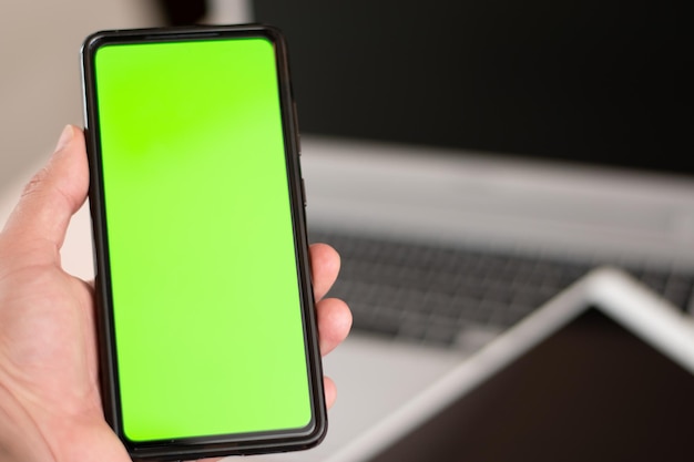 Vue verticale du téléphone portable avec incrustation verte à l'écran avec un ordinateur portable et une tablette