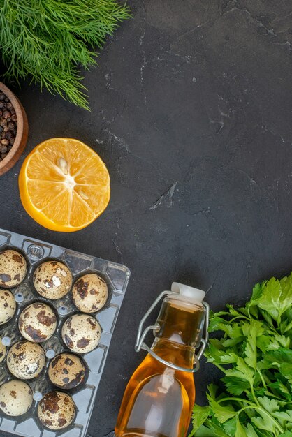 Vue verticale de l'espace vide et de la bouteille d'huile tombée en paquets verts d'oeufs de citron sur fond noir