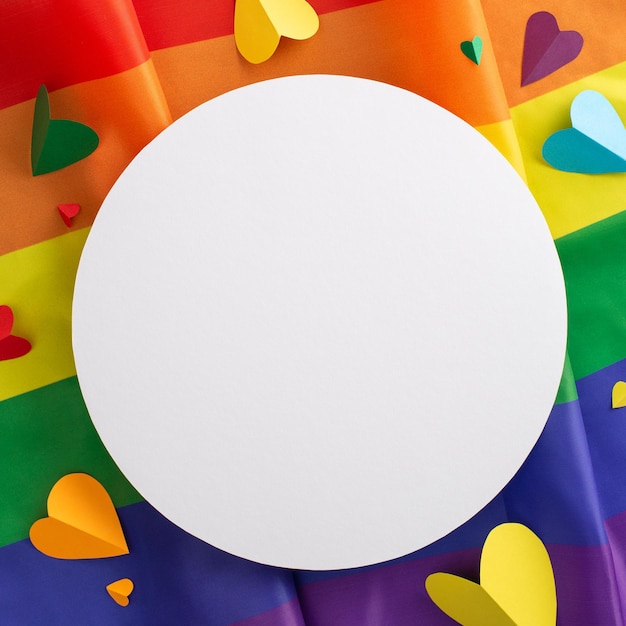 Une vue verticale plate sur les accessoires de la fierté LGBT, y compris le drapeau de l'arc-en-ciel, des cœurs colorés sur fond, un cercle vide pour la publicité incarnant le concept du mois de l'histoire LGBT et son symbolisme.