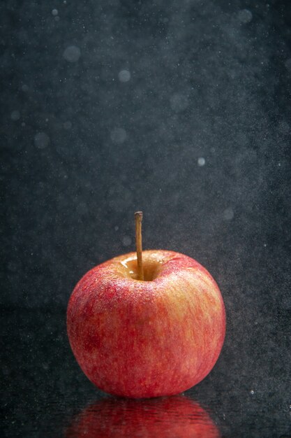 Vue verticale de pomme fraîche rouge debout sur fond de vague sombre avec espace libre