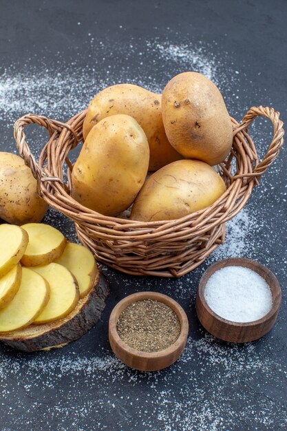 Photo vue verticale de pommes de terre fraîches entières et hachées sur des épices de planche de bois sur fond de couleurs de mélange blanc noir