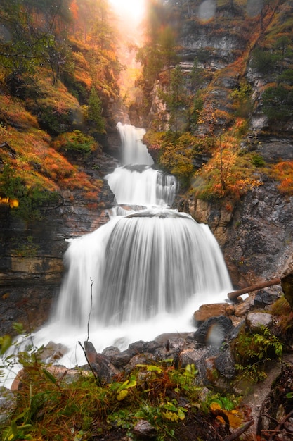 Photo vue verticale d'un ruisseau de cascade entouré de rochers en automne