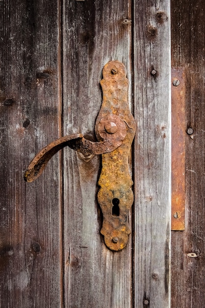 Vue de la vieille porte patinée et du bouton de porte rouillé