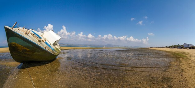 Vue d&#39;un vieux bateau abandonné échoué sur du sable sec à la plage.