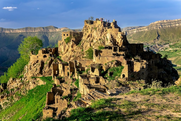 Vue sur le village abandonné de Gamsutl au sommet d'une montagne au Daghestan avec des touristes parmi les ruines