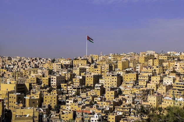 Photo vue sur la ville d'amman avec le grand drapeau de la jordanie