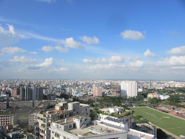 Une vue d'une ville depuis une fenêtre avec un ciel bleu et des nuages.