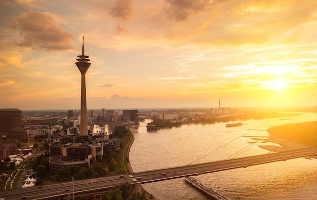 vue sur la ville de Düsseldorf au coucher du soleil avec la tour du rhin (Rheinturm) et le pont sur le rhin. idéal pour les mises en page de sites Web et de magazines