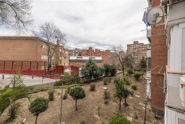 Vues d'un jardin urbain sans herbe avec de petits arbres et divers bâtiments en arrière-plan