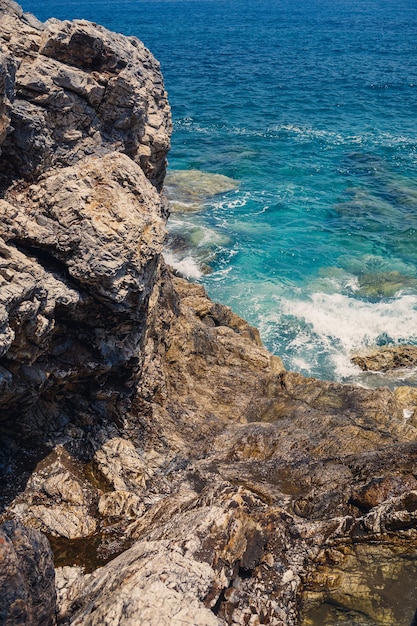 Vues magnifiques sur la mer Méditerranée bleue Roches ensoleillées vagues avec de la mousse et des éclaboussures d'eau La vague s'écrase sur les rochers sur le rivage