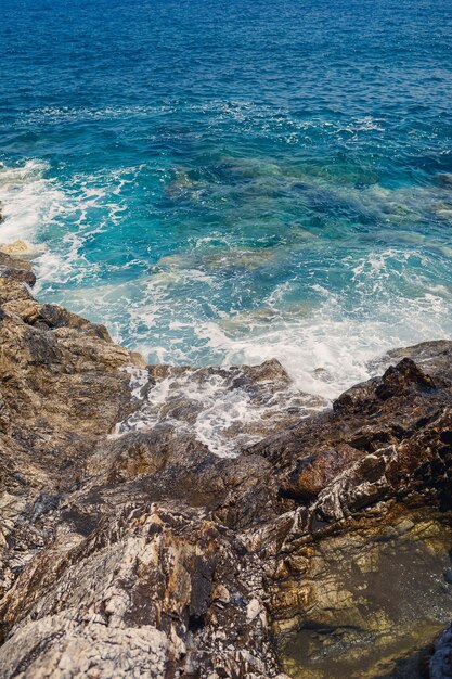 Vues magnifiques sur la mer Méditerranée bleue Roches ensoleillées vagues avec de la mousse et des éclaboussures d'eau La vague s'écrase sur les rochers sur le rivage