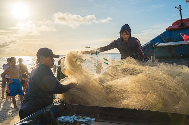 Vung Tau VIETNAM 20 AOÛT 2022 Pêcheur jetant son filet au lever ou au coucher du soleil Les pêcheurs traditionnels préparent le filet de pêche Les pêcheurs sur la plage à la pêche