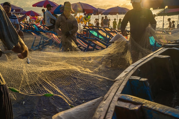 Vung Tau VIETNAM 21 AOÛT 2022 Pêcheur jetant son filet au lever ou au coucher du soleil Les pêcheurs traditionnels préparent le filet de pêche Les pêcheurs sur la plage à la pêche