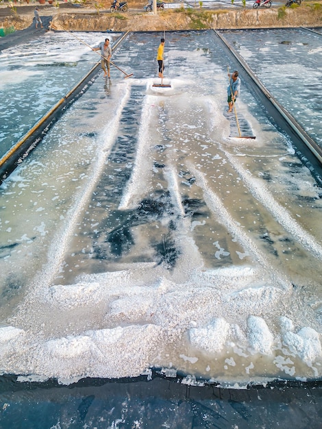 Vung Tau VIETNAM 25 FÉVRIER 2023 Le processus de sel de mer fabriqué à partir d'un tas de sel dans la casserole de sel par un travailleur du sel dans la zone rurale des champs de sel de Long Dien est l'une des destinations les plus uniques au Viet Nam