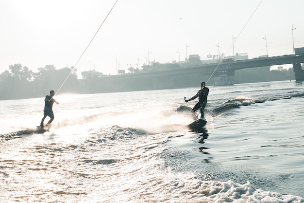Wakeboard, deux wakeboarders glissent sur l'eau avec wakeboard et créent des éclaboussures, fond vert