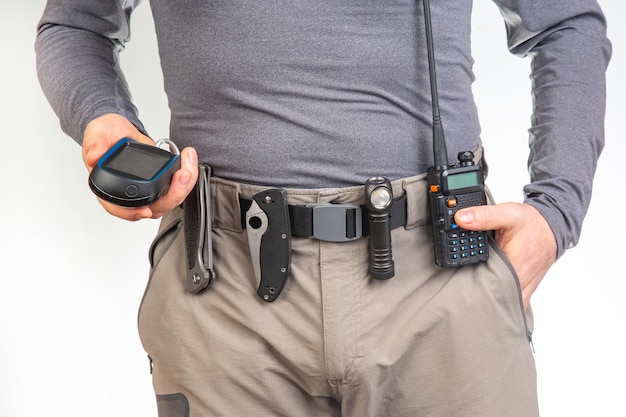 Walkietalkie, une lampe de poche, un couteau, un navigateur GPS sur la ceinture du pantalon de randonnée touristique.