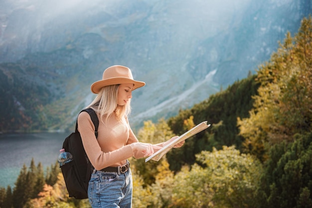 Wanderlust et concept de voyage. Fille de voyageur élégante au chapeau regardant la carte, explorant les bois. Jeune oman avec sac à dos voyageant au lac en forêt.