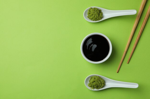 Wasabi, sauce soja et baguettes sur fond vert