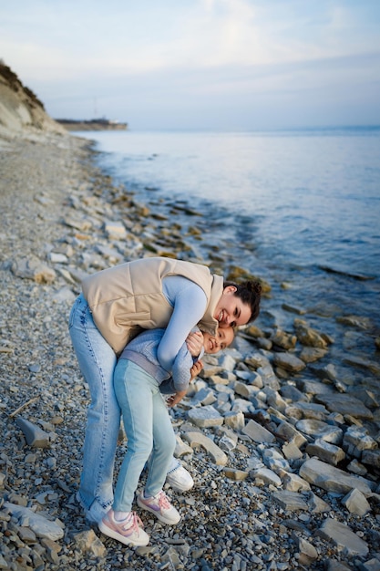 Photo week-end en famille au bord de la mer heureuse mère et fille s'amusent lors d'une promenade au coucher du soleil sur la mer