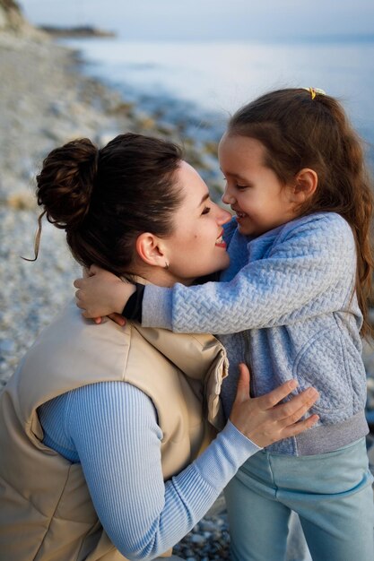 Photo week-end en famille au bord de la mer heureuse mère et fille s'amusent lors d'une promenade au coucher du soleil sur la mer