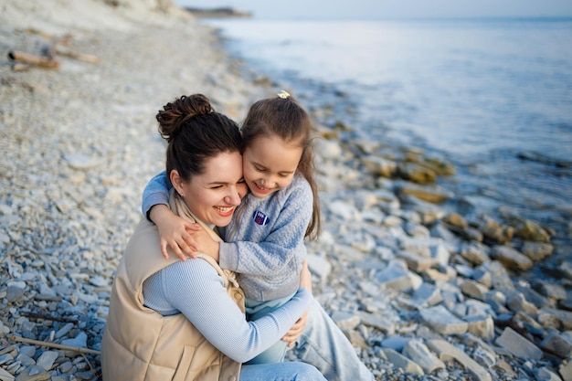 Photo week-end en famille au bord de la mer heureuse mère et fille s'amusent lors d'une promenade au coucher du soleil sur la mer