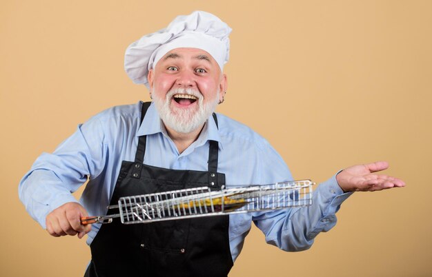 Photo week-end en famille un chef barbu mature tient une grille de grillades savoureux et délicieux griller des aliments mode de nutrition sain ustensiles de cuisine pour barbecue concept de pique-nique et de barbecue recette de grillades