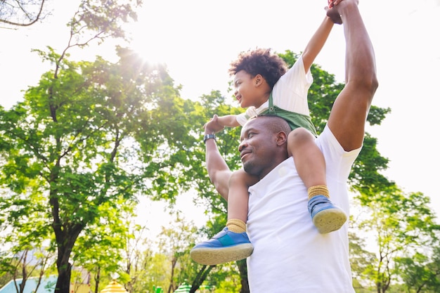 Week-end en famille Joli garçon afro-américain avec papa jouant en plein air