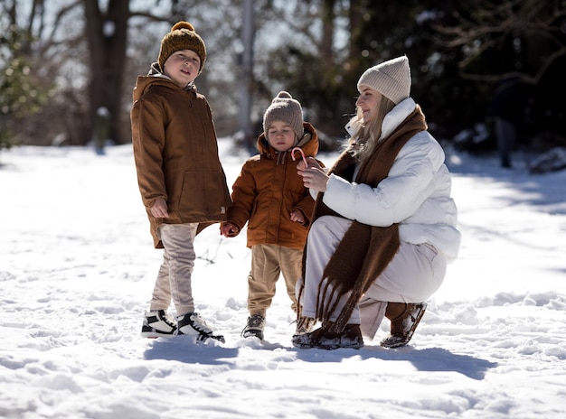 Week-end d'hiver Mère et deux fils en vêtements d'hivers chauds se promenant tout en s'amusant dans la forêt d'hivernage parmi les arbres