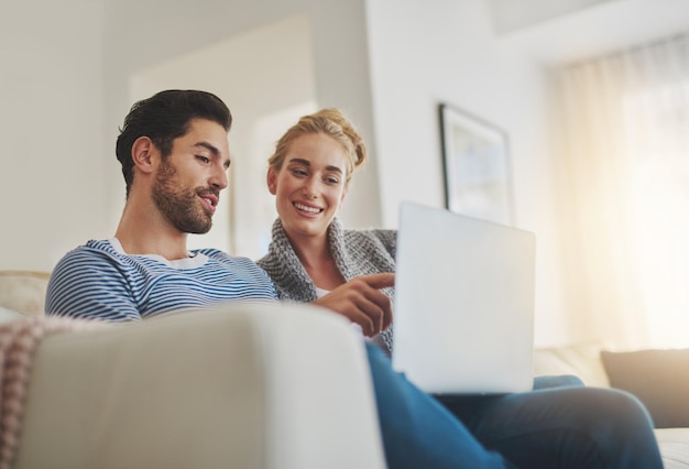 Les week-ends comme ils devraient être Photo d'un jeune couple utilisant un ordinateur portable sur son canapé à la maison