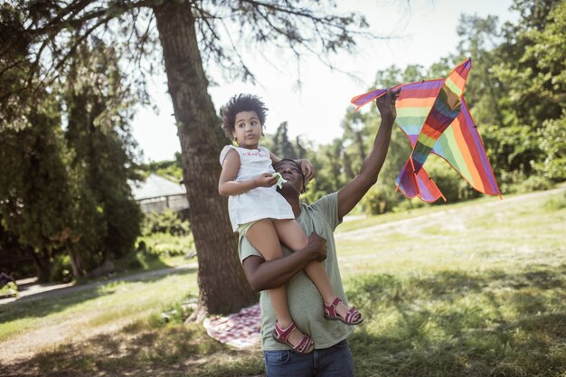 Weekend. Homme à la peau sombre et sa petite fille jouant avec un cerf-volant