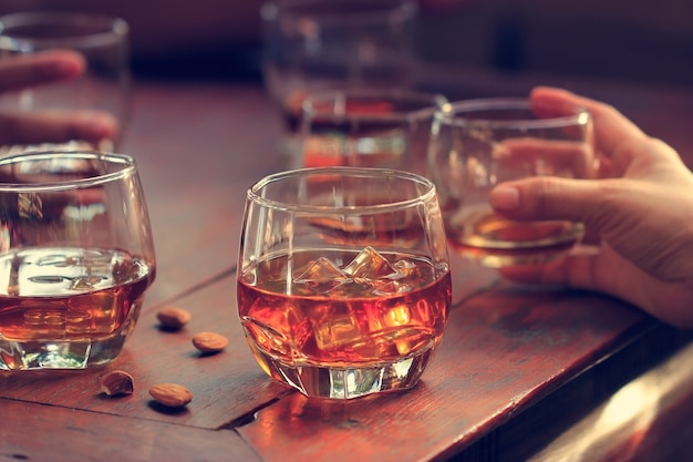 Whisky bourbon dans un verre avec de la glace sur fond de table en bois